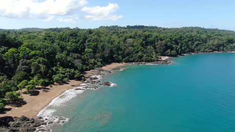 Costa-Rica-beach-drone-top-view-showing-sea,-shore-and-palm-tree-forest-in-Corcovado-National-Park-on-a-sunny-day-in-the-pacific-ocean