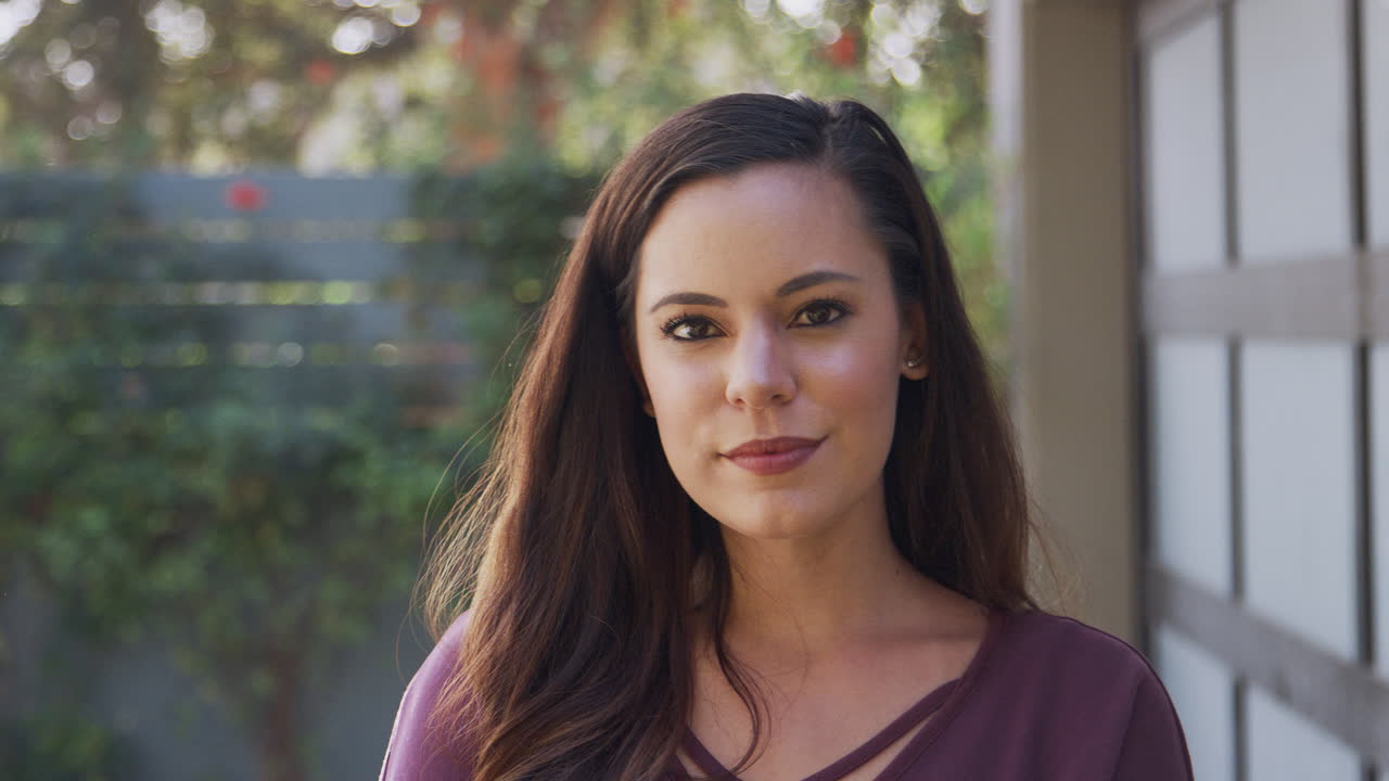 retrato de una joven hispana sonriente en el jardín en casa contra el sol abrasador