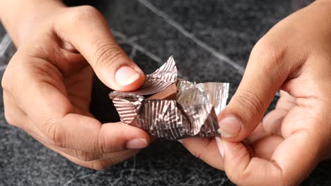 close-up of hands unwrapping a chocolate bar