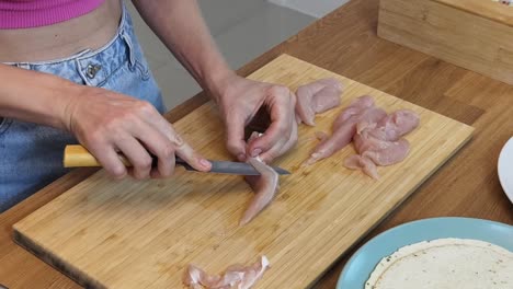 mujer cortando pecho de pollo