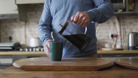 sección media de un hombre caucásico preparando café en la cocina en casa
