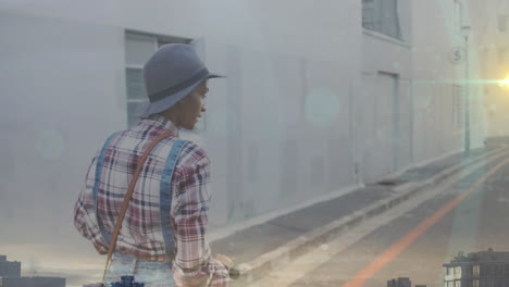 animación de puntos de luz sobre mujer biracial usando scooter en la calle.