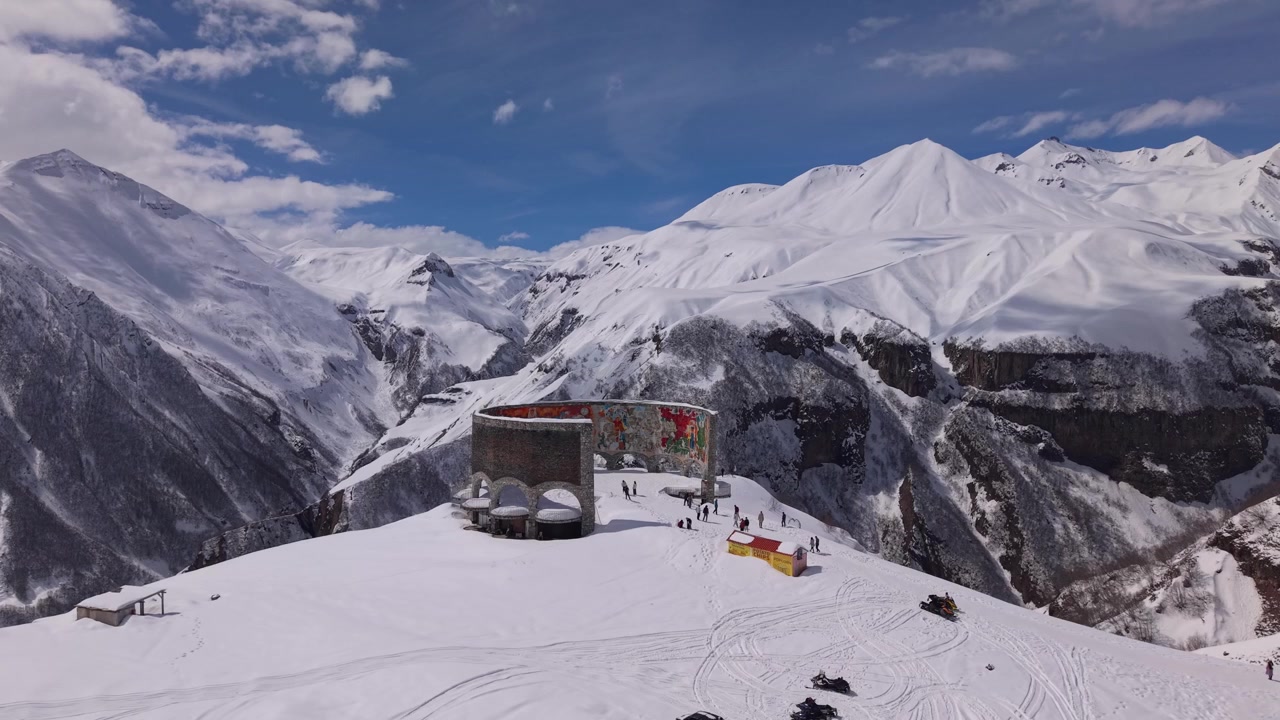 Ripresa aerea con drone in orbita del Monumento di Gudauri e del punto panoramico, che rivela alte montagne innevate e una gola spettacolare nel paesaggio georgiano
