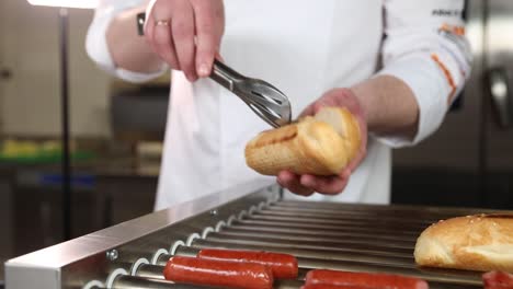 chef preparing hot dogs on a commercial grill