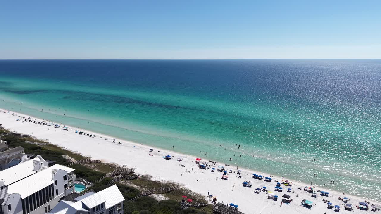 Panoramic drone fly at Gulf of Mexico resort neighborhood with turquoise ocean and white sandy beach in season, 30A, Florida, USA