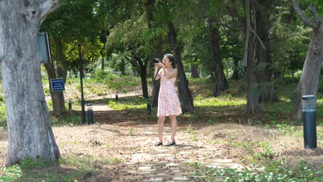 young asian woman captures location images, digital camera, woodland path