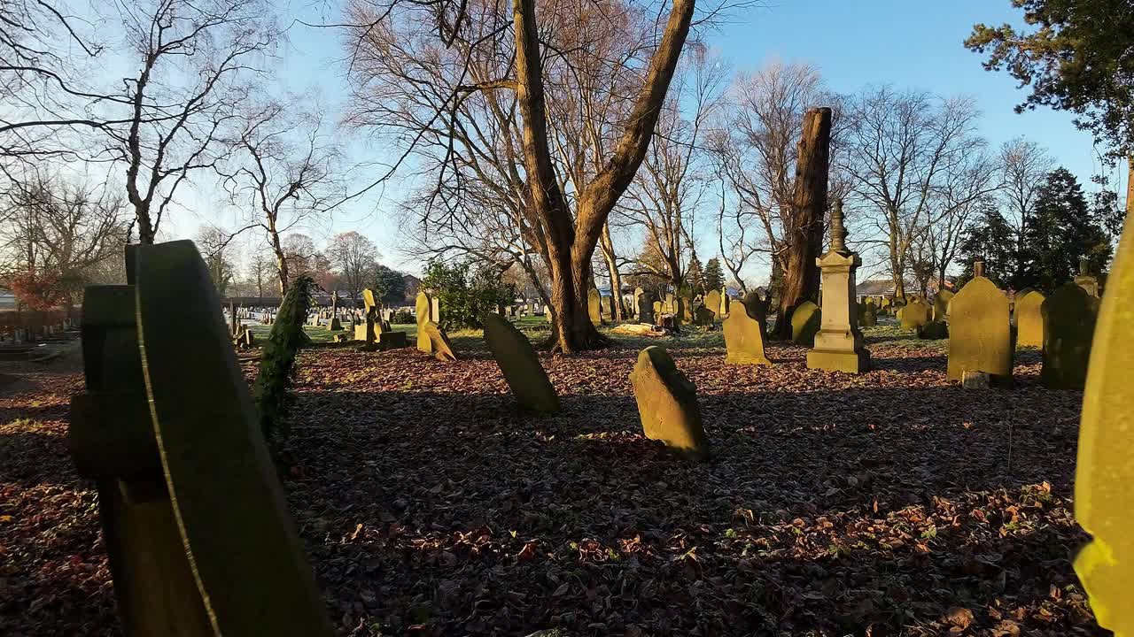 fpv는 눈 덮인 황금 시간 동안 가을 일출 교회 묘지의 비석 주위를 비행합니다.