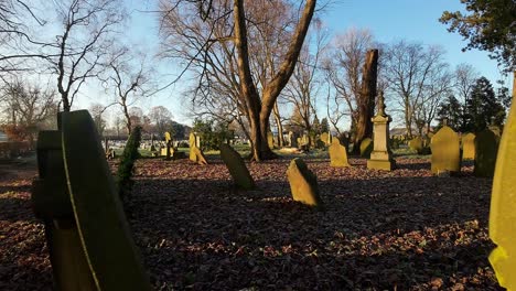 FPV-flying-around-headstones-in-autumn-sunrise-churchyard-cemetery-during-snowy-golden-hour