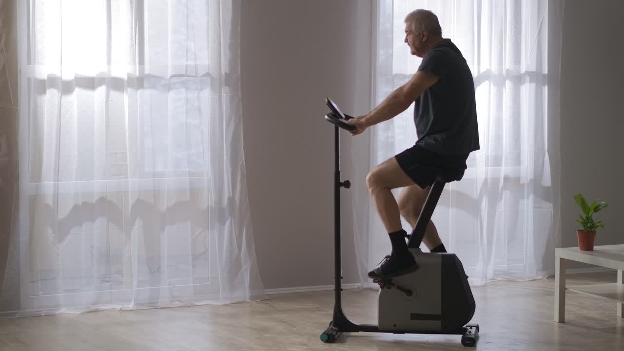 entrenamiento deportivo en bicicleta estacionaria hombre de mediana edad está girando pedales ejercicio para la salud del sistema cardiovascular mantenerse en forma