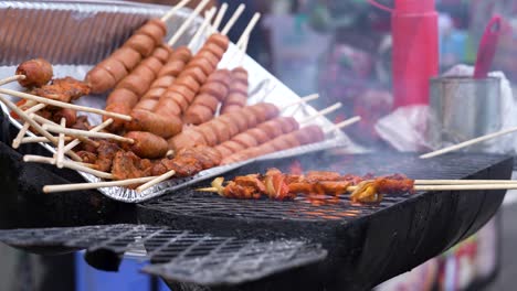 preparing street food in panama: various types of skewered food being grilled, with sausages and marinated meat