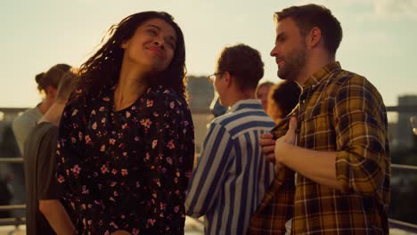 una pareja multiétnica bailando a la luz del atardecer en una fiesta.