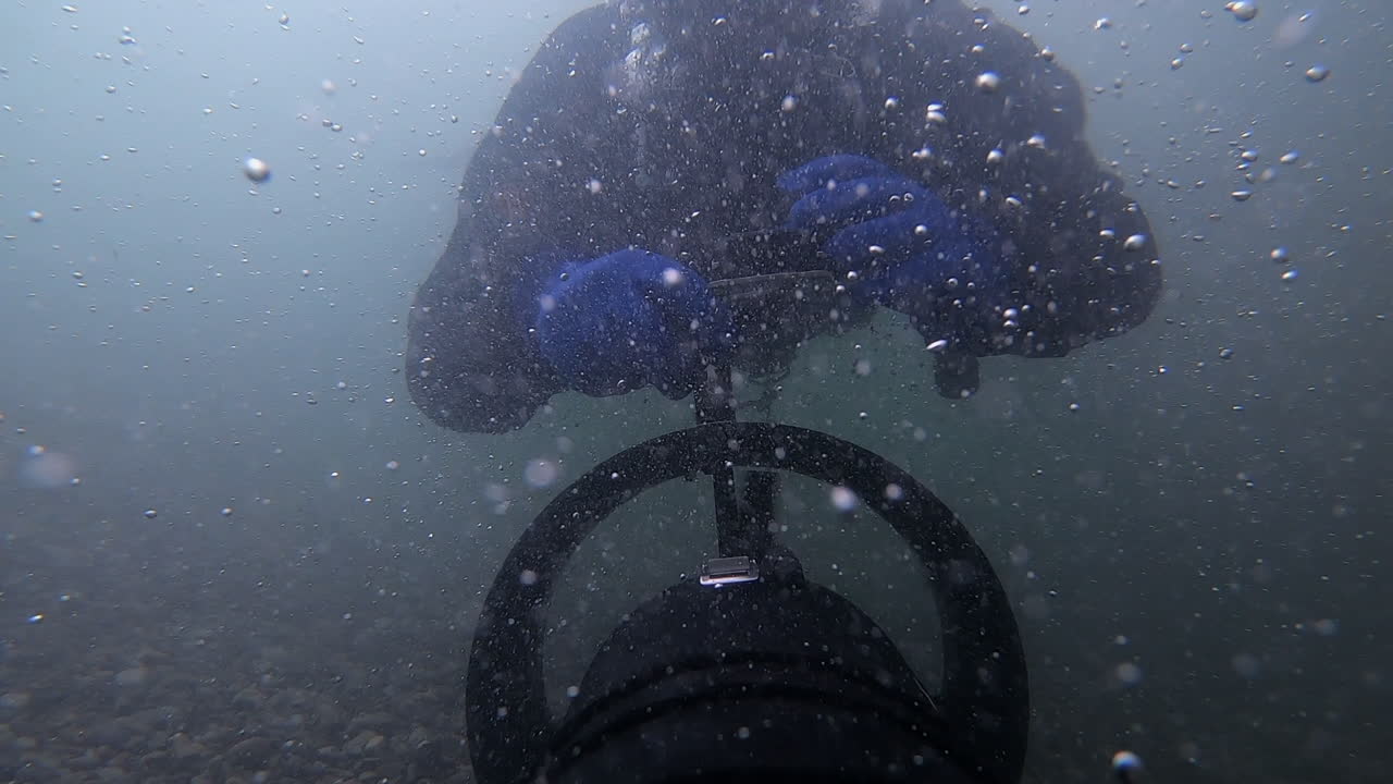 пузырьки в изобилии, когда скутер тянет технического дайвера в реку под водопадом