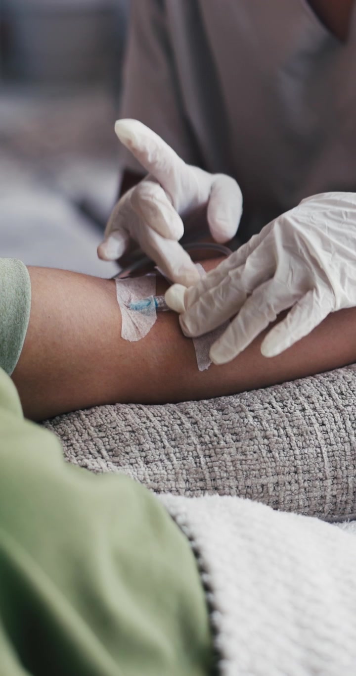 Infermiere che fissa un catetere endovenoso sul braccio del paziente