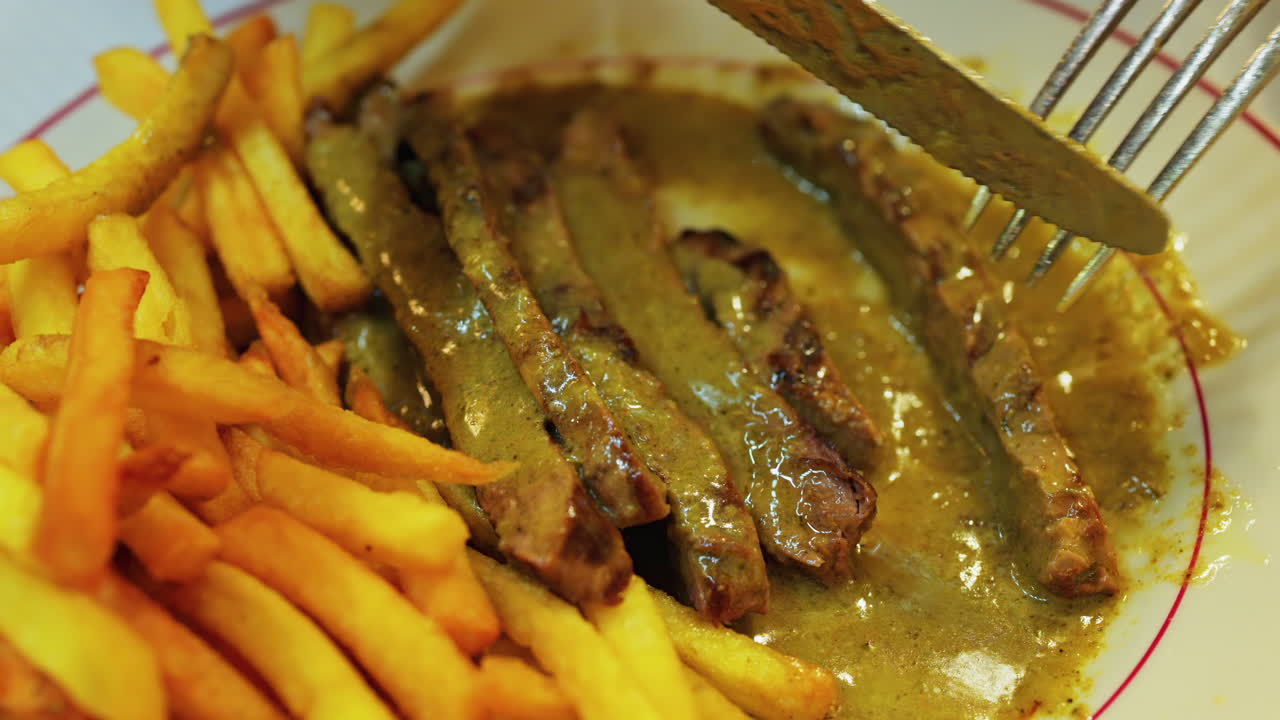 Close up of a plate of fries with meat and green sauce on a plate