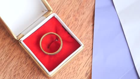la mano de una mujer colocando un anillo en una caja roja