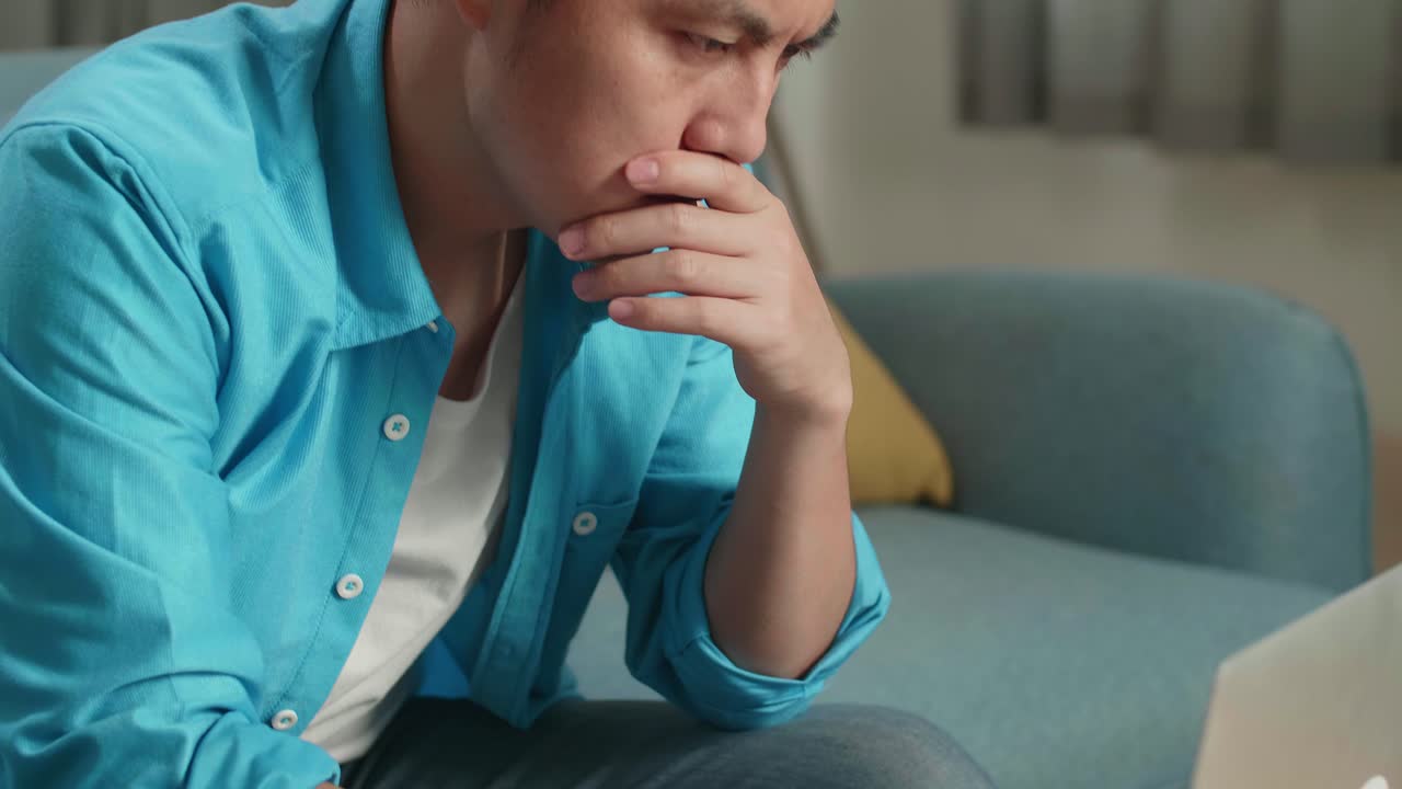 집에서 노트북으로 타이핑하는 동안 걱정하는 아시아 남자의 클로즈업