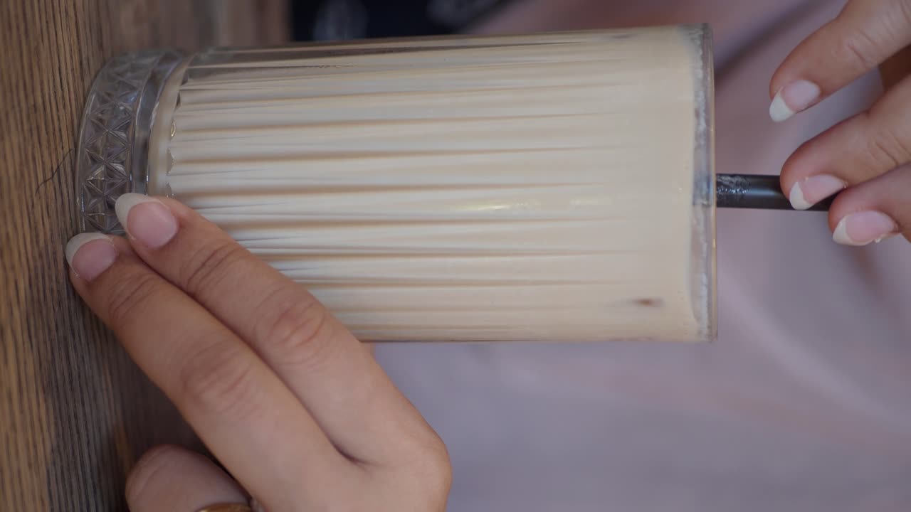 Donna che tiene un bicchiere di tè/caffè freddo