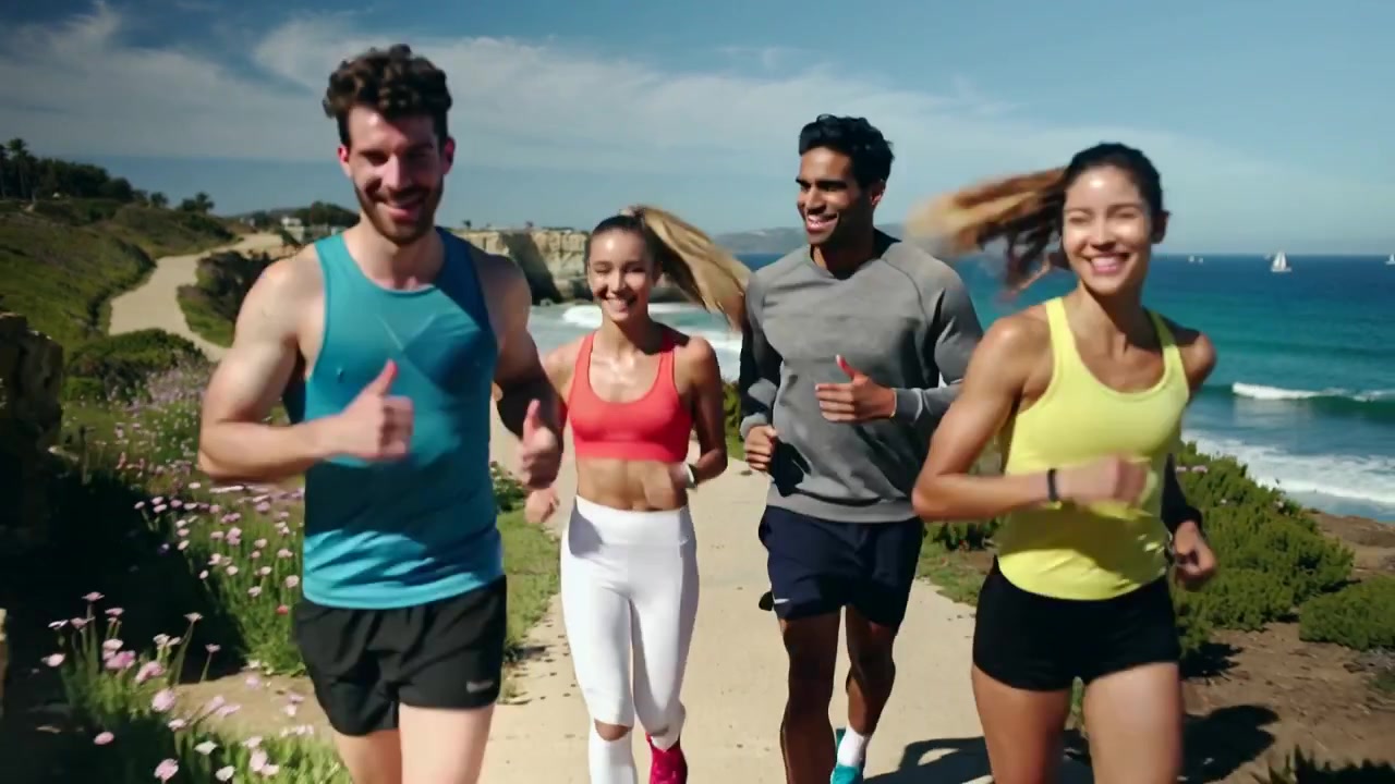 Adulti che corrono lungo un sentiero sulla scogliera in una giornata di sole, allenandosi in abbigliamento sportivo e indossando orologi.
