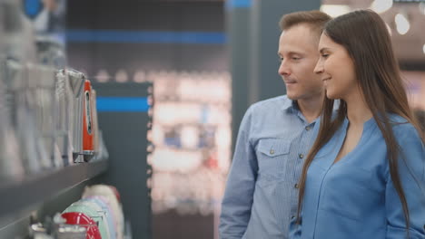 a man and woman hold in their hands an electric kettle in a store choosing before buying in appliances store