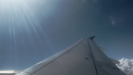 airplane wing with sunlight and clouds