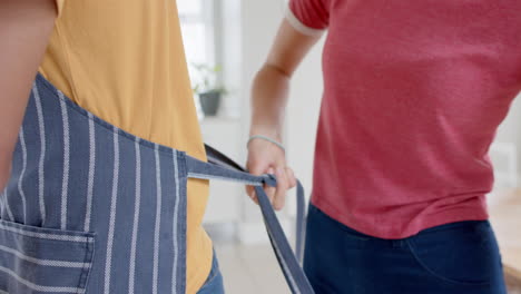 diverse couple cooking and wearing aprons in kitchen, slow motion