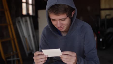 a teenage boy smiles while looking at a photograph