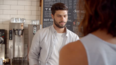 barista taking card payment from a customer at a coffee shop