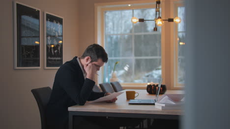 focused-man-sitting-at-dining-table-working