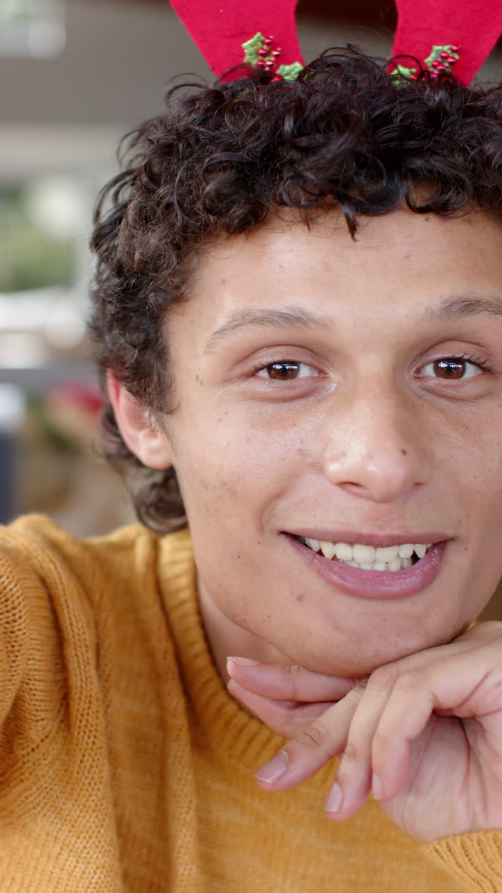 Vertical video of happy biracial man lhaving video call at home, slow motion