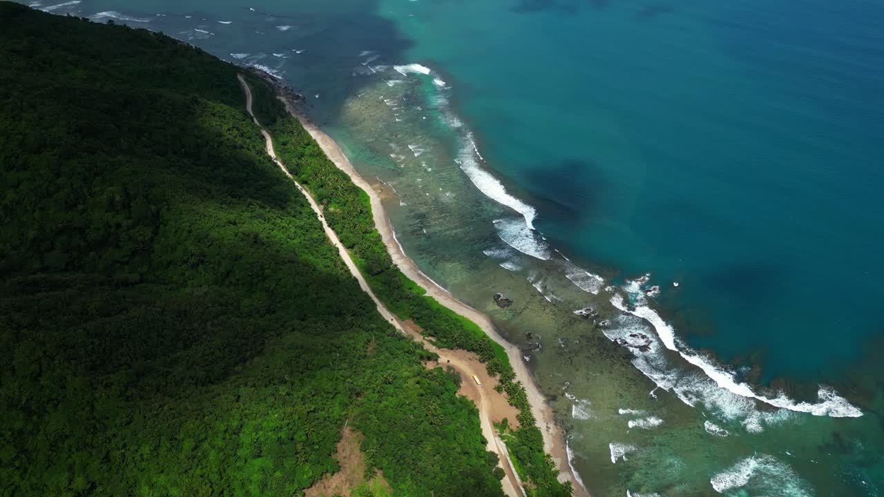 Upward tilt aerial shot of Dingalan, Aurora, revealing lush green hills and coastline as drifting clouds cast dramatic shadows across the turquoise expanse of the Philippine Sea