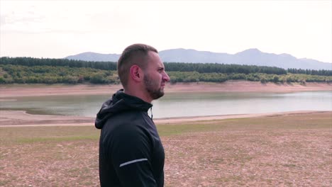 young man walking on the beach of a small lake enjoying the beautiful environment