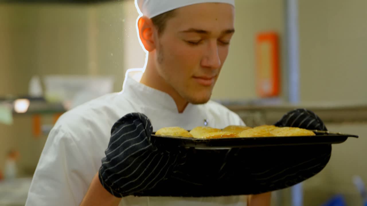 chef masculino oliendo bandeja de galletas en la cocina 4k