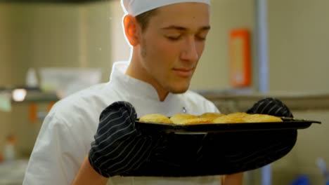 Male-chef-smelling-tray-of-cookies-in-kitchen-4k