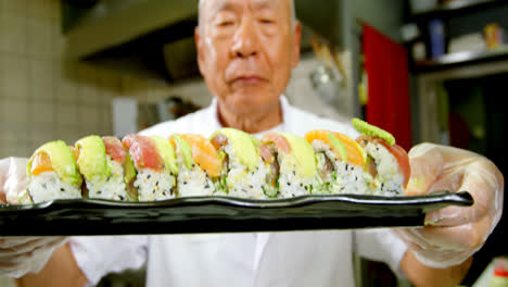 chef masculino sosteniendo una bandeja de sushi en la cocina 4k