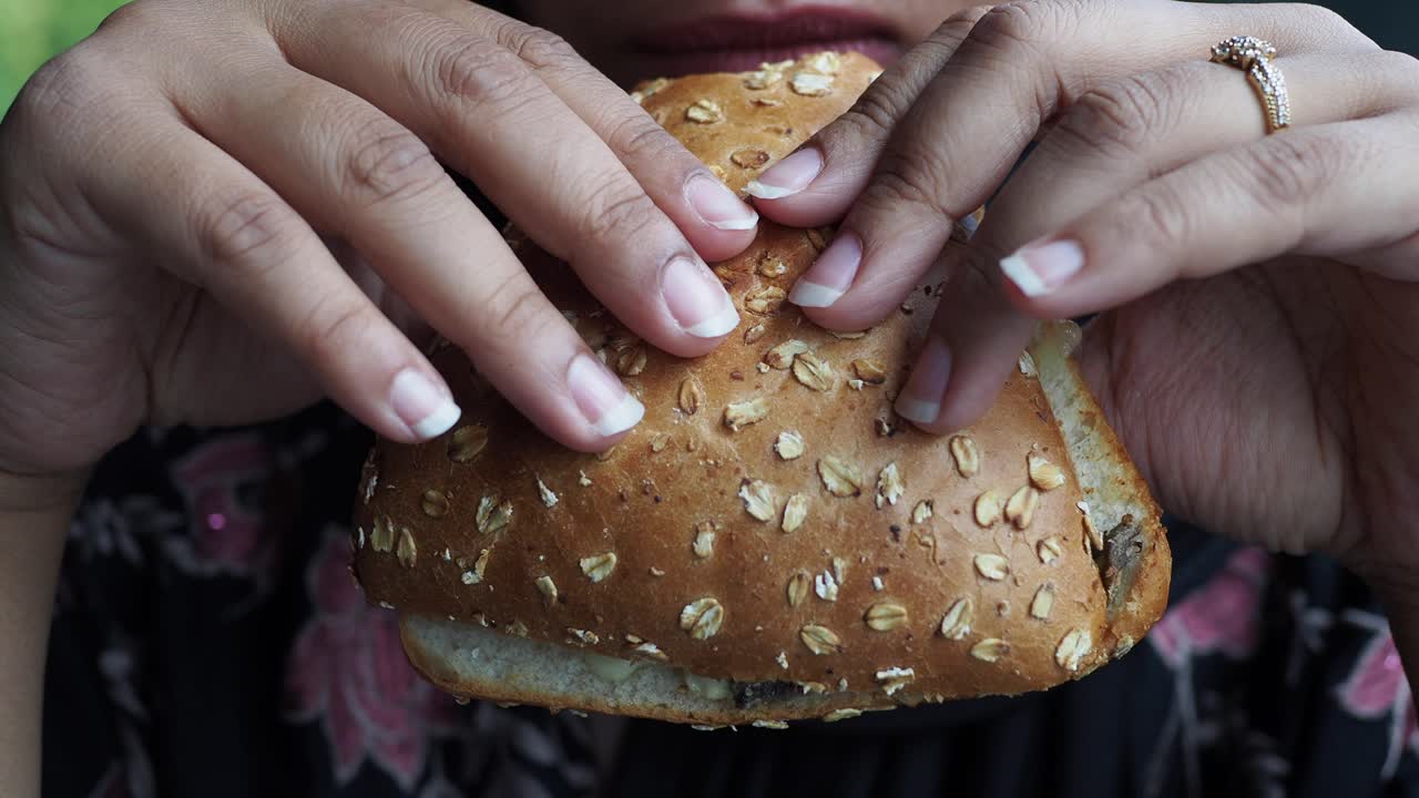 Una mujer comiendo un sándwich.