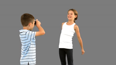 Hermano-Tomando-Fotografías-De-Su-Hermana-Saltando-En-Una-Pantalla-Gris