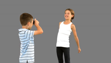 hermano tomando fotos de su hermana saltando en la pantalla gris