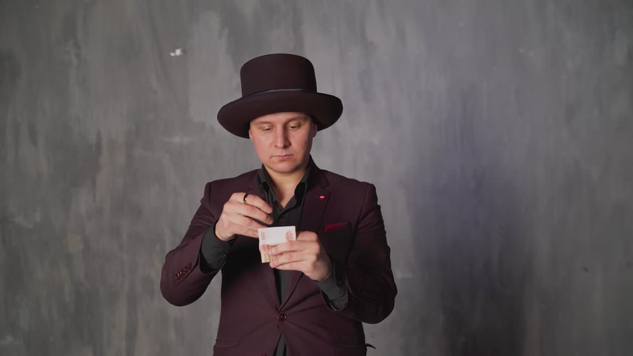 el mago y la cuenta de dinero. el mago está sosteniendo el dinero. el mágico muestra el truco, perfora el billete con una pluma