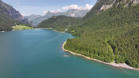 aerial - klöntalersee with forested shoreline and mountains in kanton glarus, switzerland