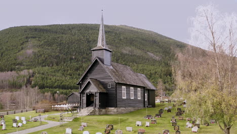 Exterior-De-Una-Antigua-Iglesia-Y-Cementerio-De-Madera-En-Sel,-Noruega---Toma-Aérea-De-Drones