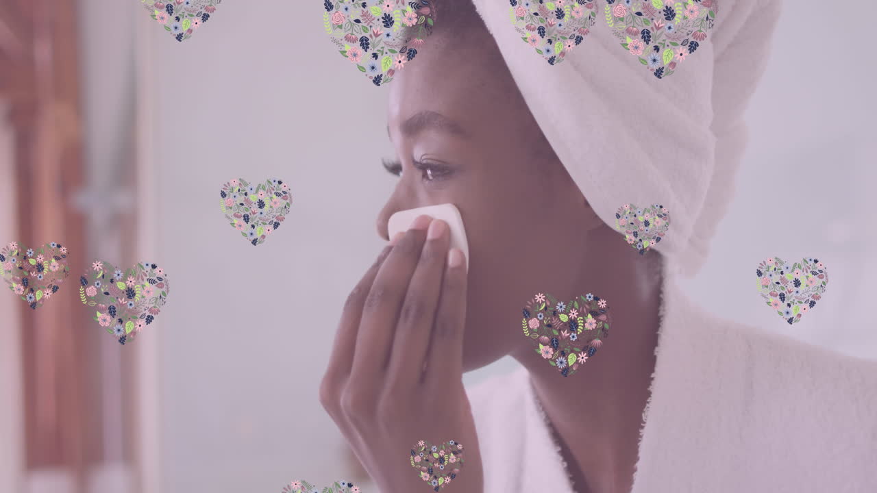 animación de corazones florales sobre una feliz mujer afroamericana limpiando la cara en el baño