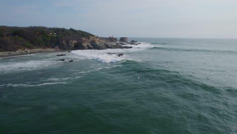 toma aérea de un surfista montando una ola con otros esperando
