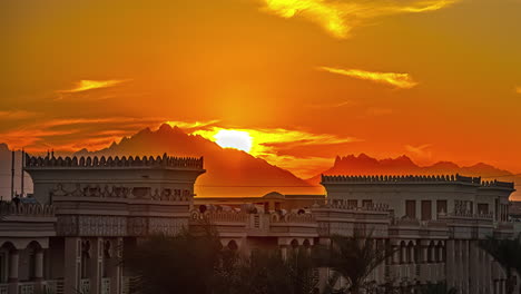 Zeitraffer-Des-Sonnenuntergangs-über-Der-Bergkette-Im-Hintergrund-über-Einem-Resortgebäude-Am-Abend