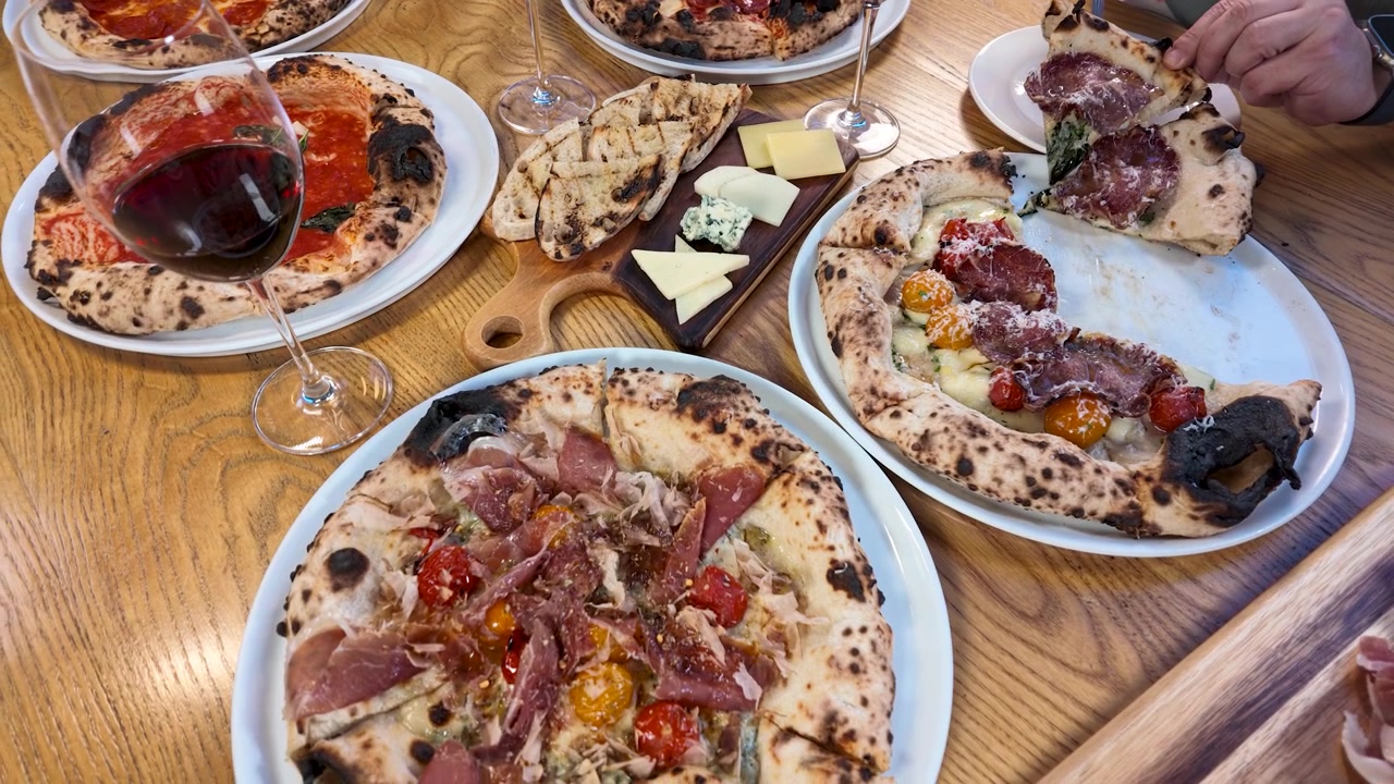 Freunde genießen Gourmet-Pizza und Rotwein in einem Restaurant
