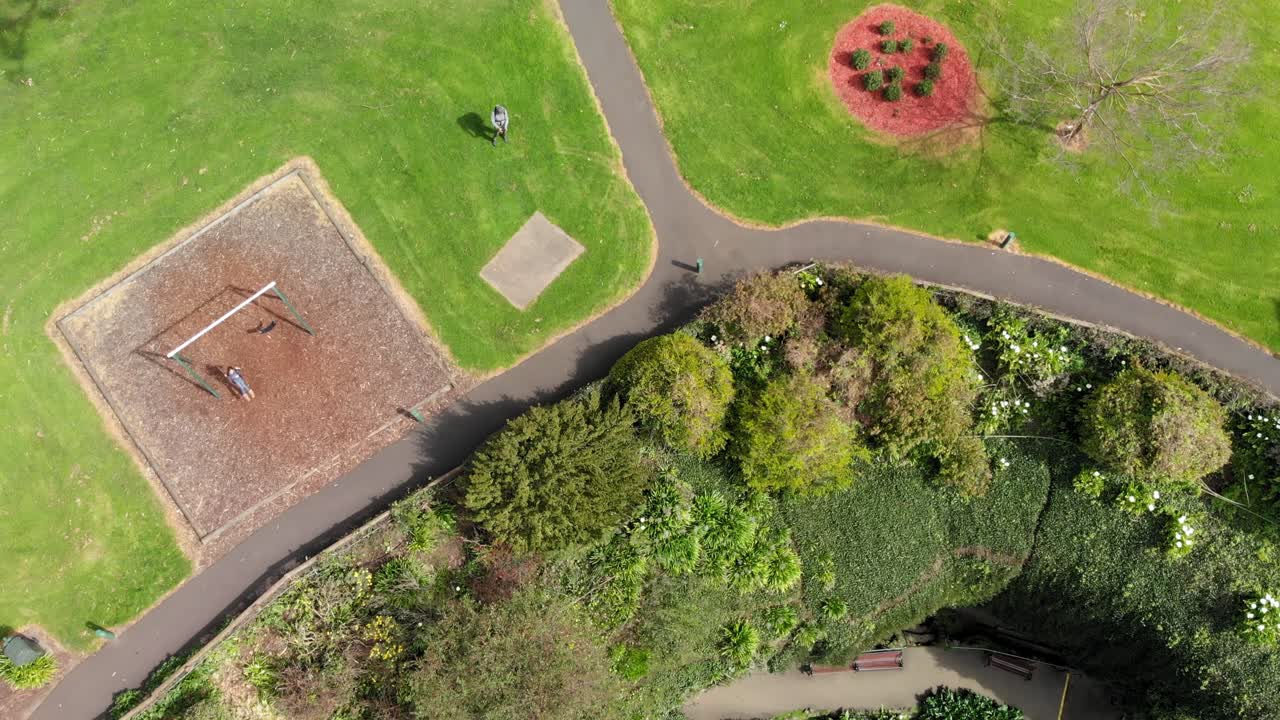 Girl swing on playground by Umpherston Sinkhole Australia, aerial view