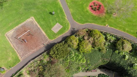 Girl-swing-on-playground-by-Umpherston-Sinkhole-Australia,-aerial-view