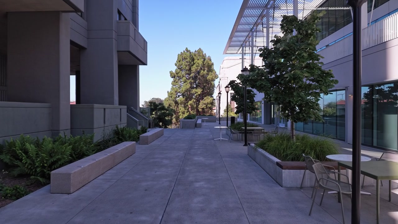 Arquitetura moderna do campus da Universidade da Califórnia, Berkeley, com uma passarela de concreto que leva através de uma praça vazia ladeada por edifícios contemporâneos em um dia claro e ensolarado