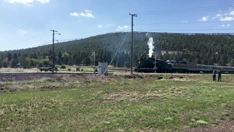 a vintage stream engine drags a modern train engine and cars through the flagstaff crossing, arizona