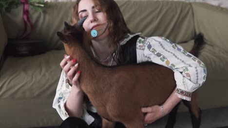 el retrato representa a una hermosa joven caucásica abrazando una pequeña cabra en auténtica ropa bordada ucraniana