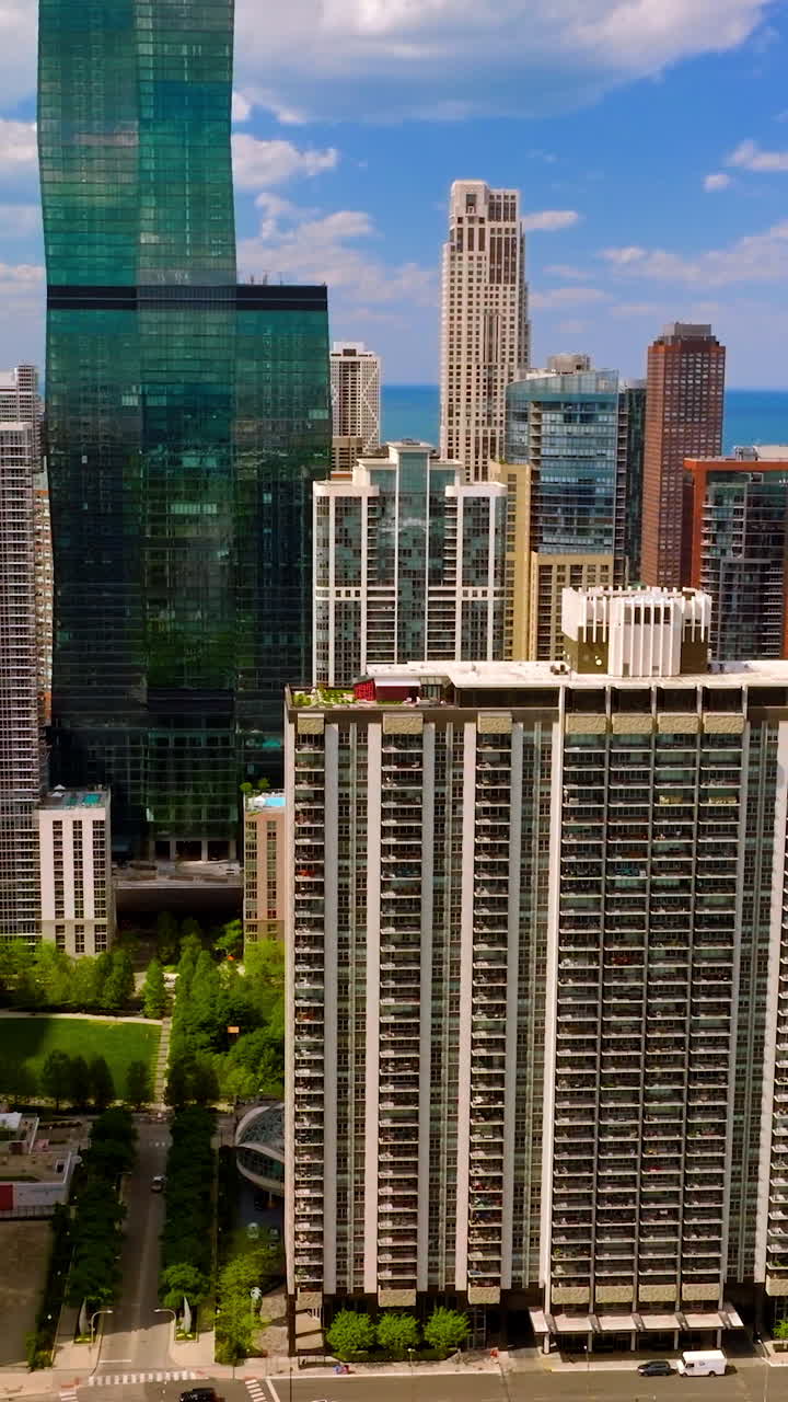 Multi-storied buildings and skyscrapers on beautiful sunny day. Fantastic Chicago architecture at the backdrop of blue sky and blue lake water. Vertical video